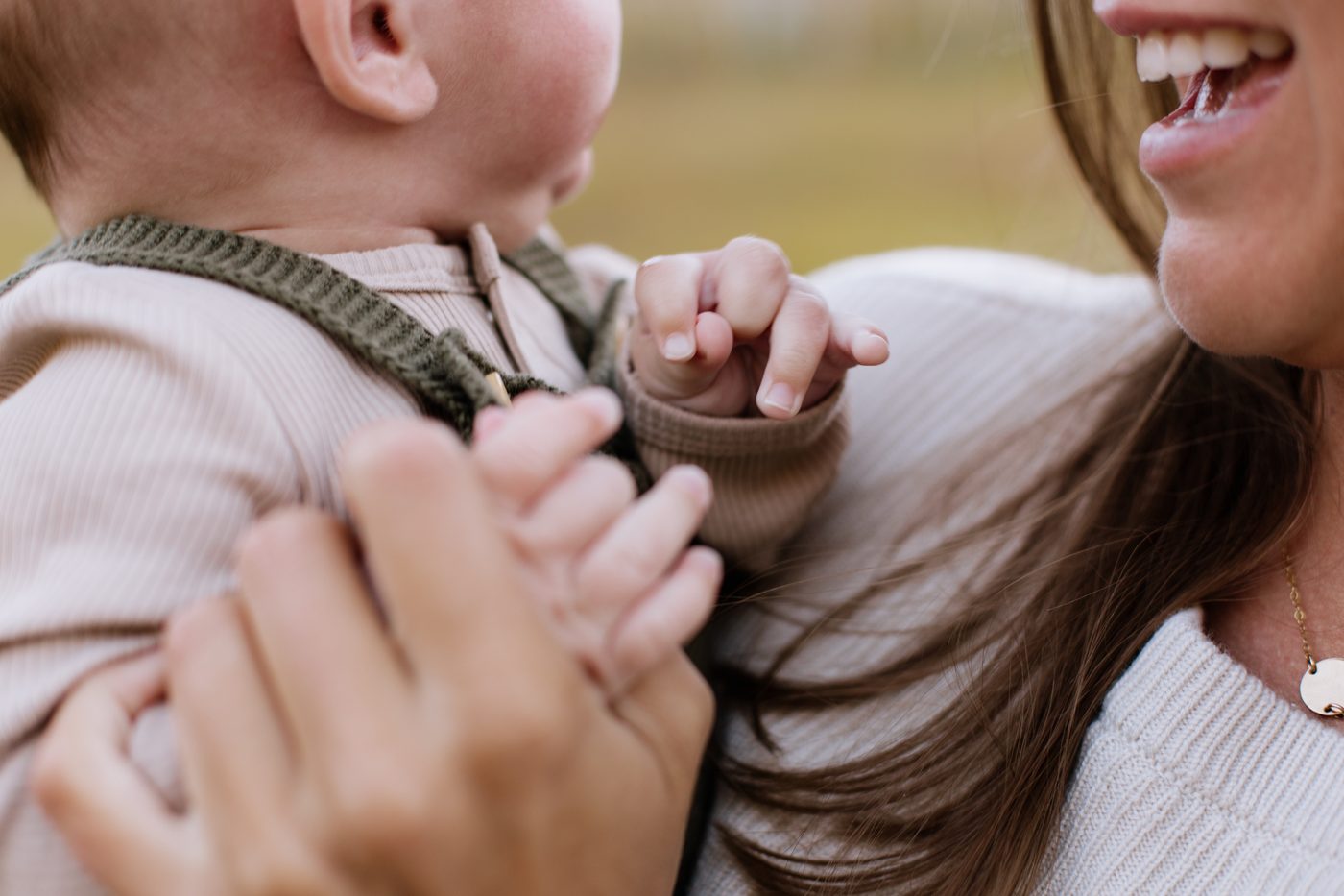 Close-up of a baby's tiny hands while mom laughs