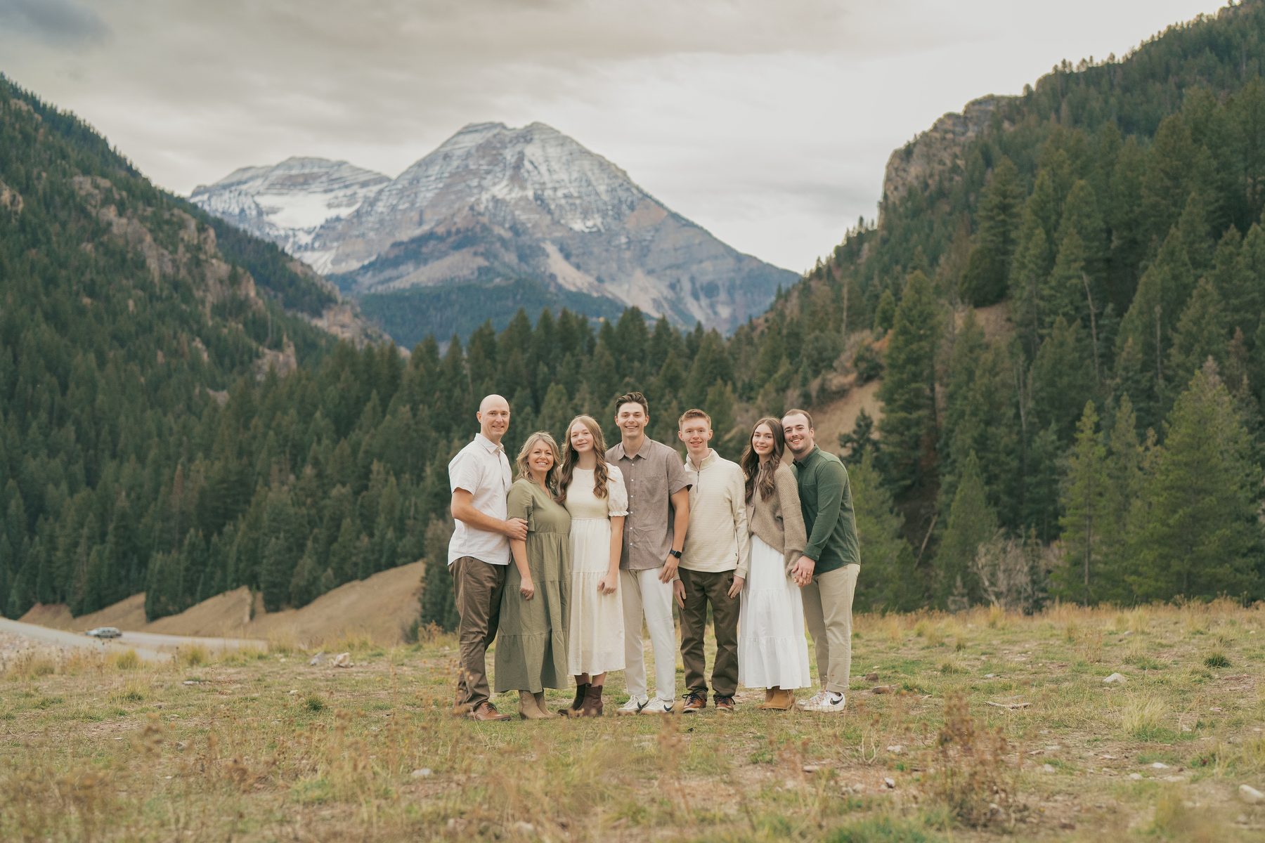 Family of seven standing before a snowy Utah peak and pine forest