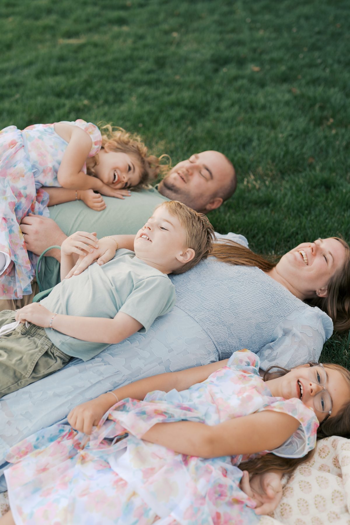 Family in pastels lying on the grass laughing together