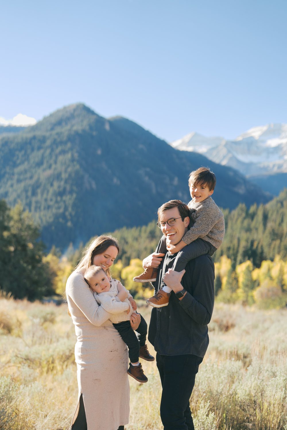 Family of four in a mountain meadow with Utah peaks behind them
