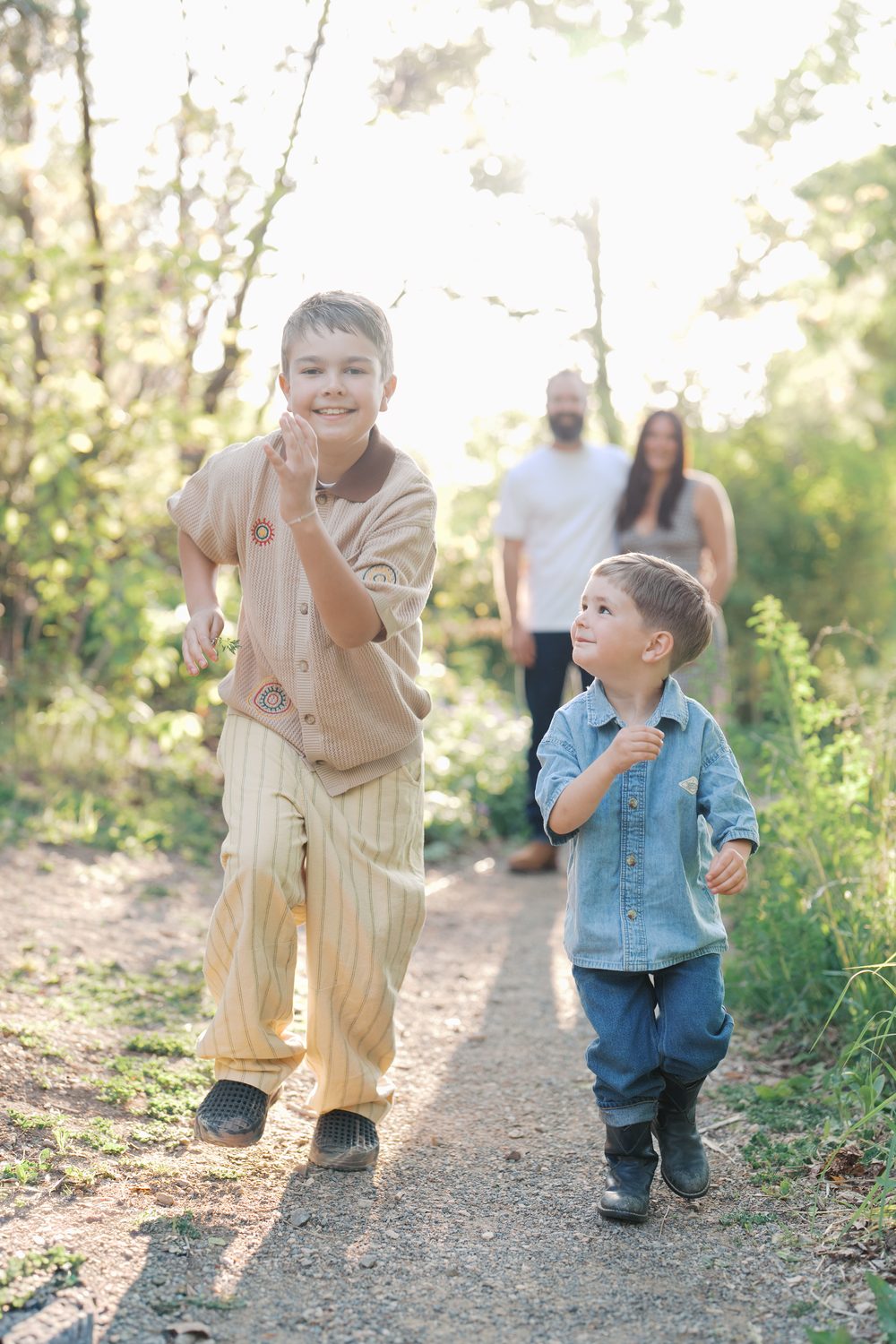 Two brothers running up a sunny trail ahead of their parents